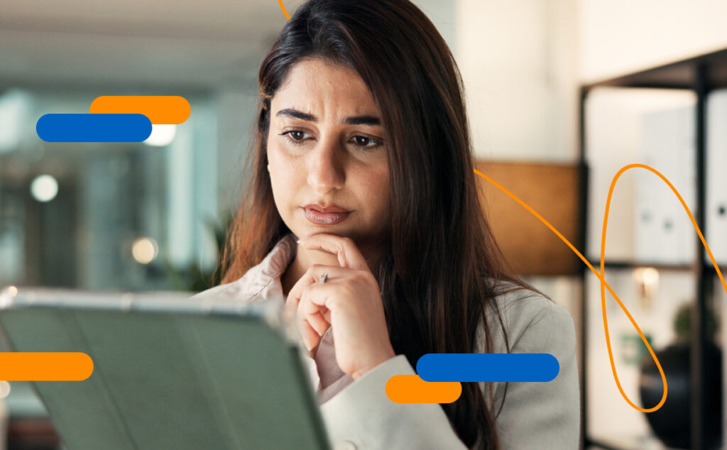 Businesswoman looking intently at a tablet and touching her chin, thinking about security practices for SMEs in an office environment
