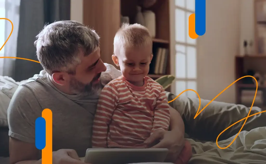 Padre e hijo pequeño mirando una tablet, representando cómo solicitar el permiso de paternidad de manera telemática