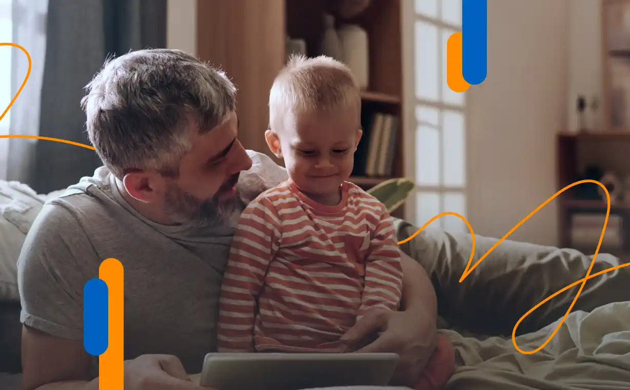 Padre e hijo pequeño mirando una tablet, representando cómo solicitar el permiso de paternidad de manera telemática